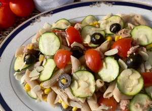 Foto di Pasta fredda integrale, con tonno mais olive nere, pomodorini, zucchina a fette sottili e mandorle