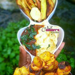 A picture of Fried plantain,potato chips,fried egg and tomatoes sauce.