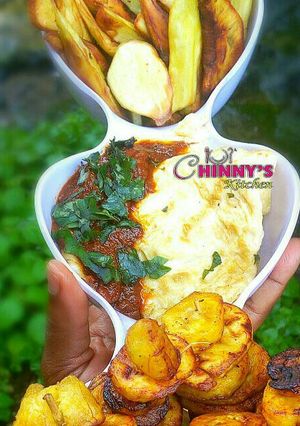 A picture of Fried plantain,potato chips,fried egg and tomatoes sauce.