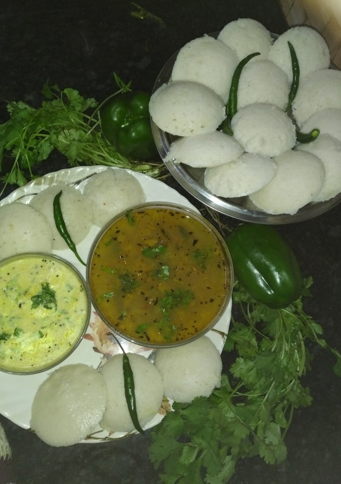 A picture of Idli with sambhar and chutney.