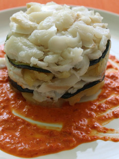 Una foto de Timbal de bacalao confitado sobre salsa de pimientos de piquillos