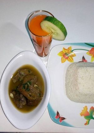 A picture of Boiled rice with goat meat peppersoup and watermelon juice.