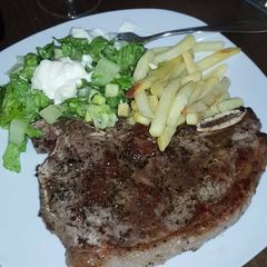 A picture of Grilled meat with chips and lettuce.