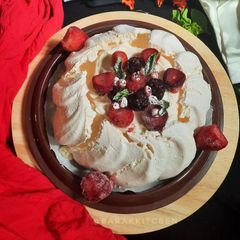 A picture of Pavlova Served with Whipped Cream and Fruits.