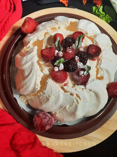 A picture of Pavlova Served with Whipped Cream and Fruits.