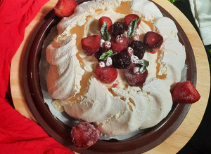 A picture of Pavlova Served with Whipped Cream and Fruits.