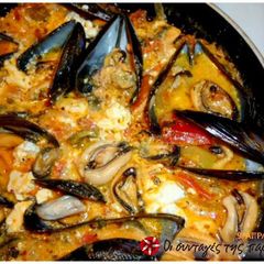 A picture of Steamed mussels with colored peppers and feta cheese.