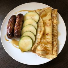 A picture of Brunch pancakes with sausage, pear and maple syrup.