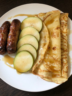 A picture of Brunch pancakes with sausage, pear and maple syrup.
