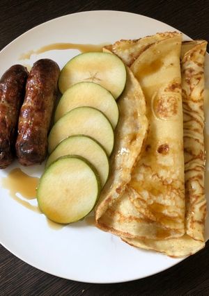 A picture of Brunch pancakes with sausage, pear and maple syrup.