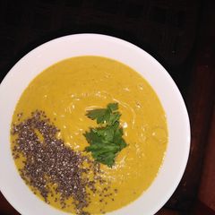 A picture of Pumpkin soup with chia seeds toppings, garnished with coriander.