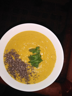 A picture of Pumpkin soup with chia seeds toppings, garnished with coriander.