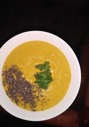 A picture of Pumpkin soup with chia seeds toppings, garnished with coriander.