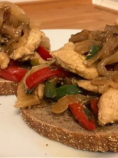 Una foto de Tostas con pollo, cebolla y pimientos