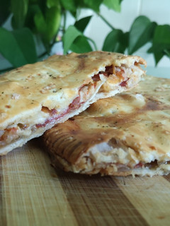 Una foto de Empanada de jamón ibérico y rulo de cabra con tomate y cebolla