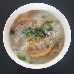 A picture of Congee with pork mince and watercress.