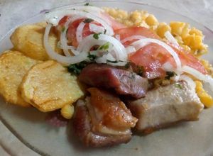 Una foto de Chicharrón de cerdo con mote,(maíz amarillo),papas doradas