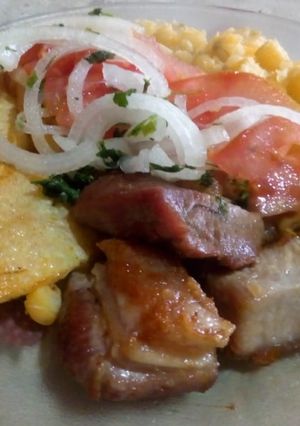 Una foto de Chicharrón de cerdo con mote,(maíz amarillo),papas doradas