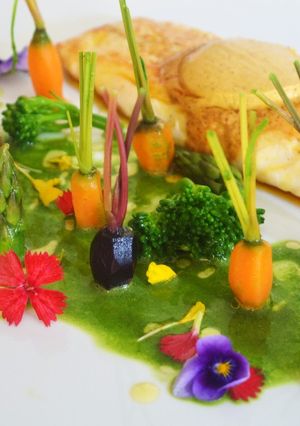 Una foto de Lubina con mantequilla de especias, jardín de verduritas y licuado de espinacas y perejil