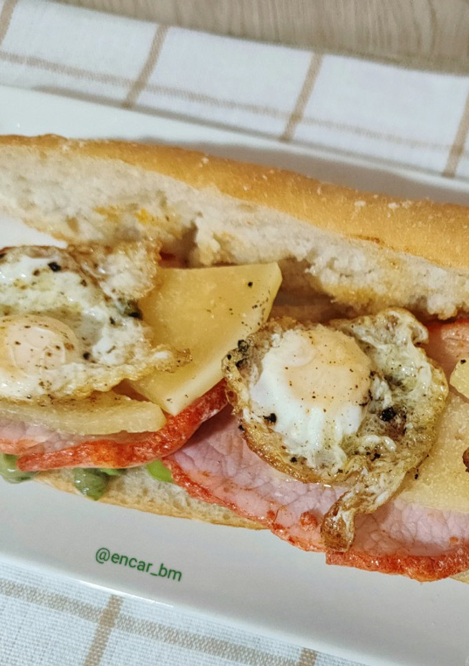 Una foto de Bocadillo de lomo adobado con habitas y huevos de codorniz