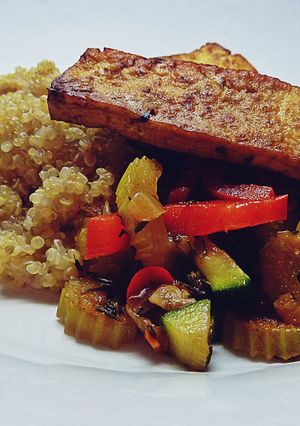 A picture of Tofu steak with fried vegetables and quinoa.