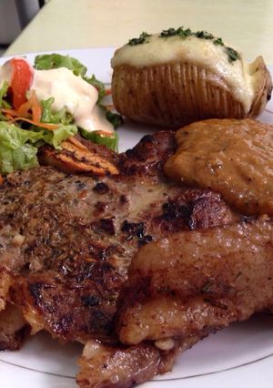 A picture of Rib Eye Steak with German Peppermint Sauce, Yogurt Salad, Baked Potato with Cheese.