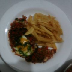 A picture of Shakshuka accompanied by French fries.