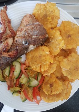 Una foto de Pescado frito con patacones y ensalada de pepino