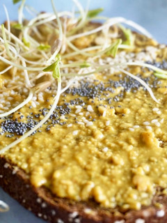 Una foto de Crema de cacahuete de orégano, cúrcuma, canela y jengibre con brotes de lentejas