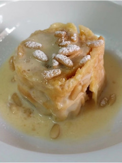 Una foto de Bracito de masa choux relleno de crema de turrón de yema quemada y crema inglesa