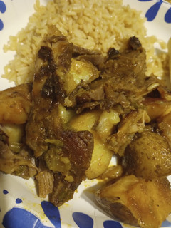 A picture of Oven Roasted Goat with Vegetables and Rice.