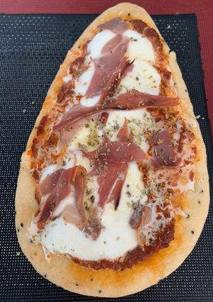 Une photo de Pizza naan au jambon sec & fior di latte avec du Pesto rosso & une salade