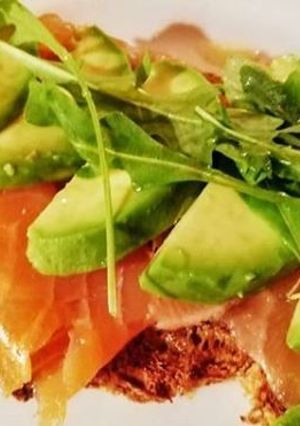 Una foto de Tostada de salmón, aguacate, queso fresco y rúcula