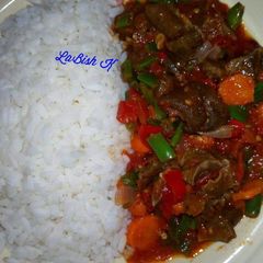 A picture of Rice  with stir fry goat meat sauce.