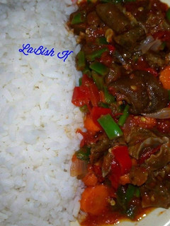A picture of Rice  with stir fry goat meat sauce.
