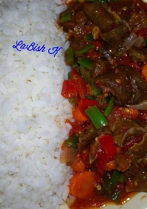 A picture of Rice with stir fry goat meat sauce.
