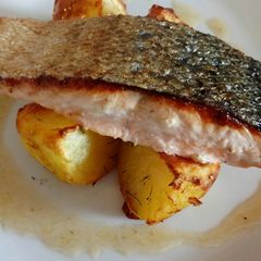 A picture of Pan fried salmon on an open jacket with dill and butter.