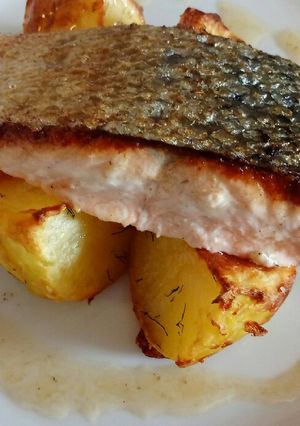 A picture of Pan fried salmon on an open jacket with dill and butter.