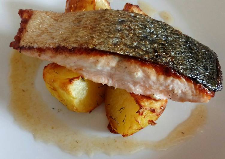 Pan fried salmon on an open jacket with dill and butter