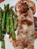 Pescado al horno sobre tomates, con espárragos, panceta y hebras de queso