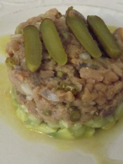 Una foto de Timbal de bonito y aguacate con cebolleta y pepinillos