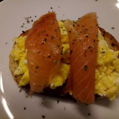 A picture of Smoked salmon and scrambled egg on toasted oregano bread.