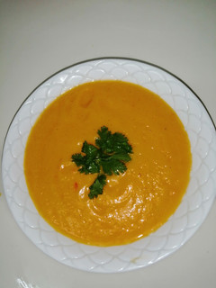 A picture of Pumpkin soup garnished with coriander.