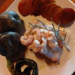 A picture of Salmón con salsa de camarones al coco y eneldo con papas moradas.