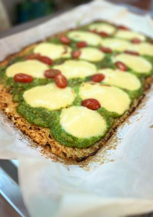 Una foto de Pizza de coliflor con pesto de espinacas estilo caprese