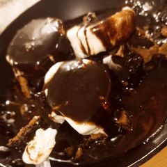 A picture of Flourless brownies with mexican chocolate sauce and Ice cream.