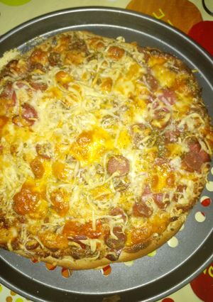 Una foto de Pizza con queso crema semi curado, salchichas y bacon