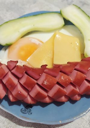 Фото Жареная сосиска с яйцом, сыром и свежим огурцом.
