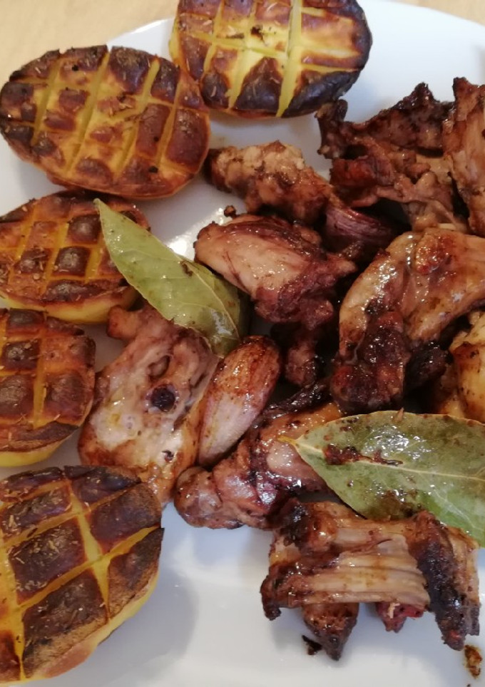 Una foto de Conejo con ajo y laurel acompañado de patatas asadas