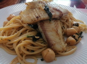 Una foto de Merluza austral con espaguetis y ostiones al ajillo con cebollín y cilantro. 